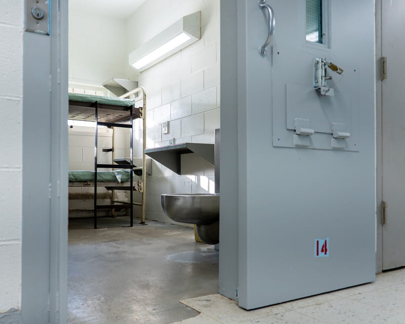 A prison cell with a bunkbed, a sink, and a toilet.