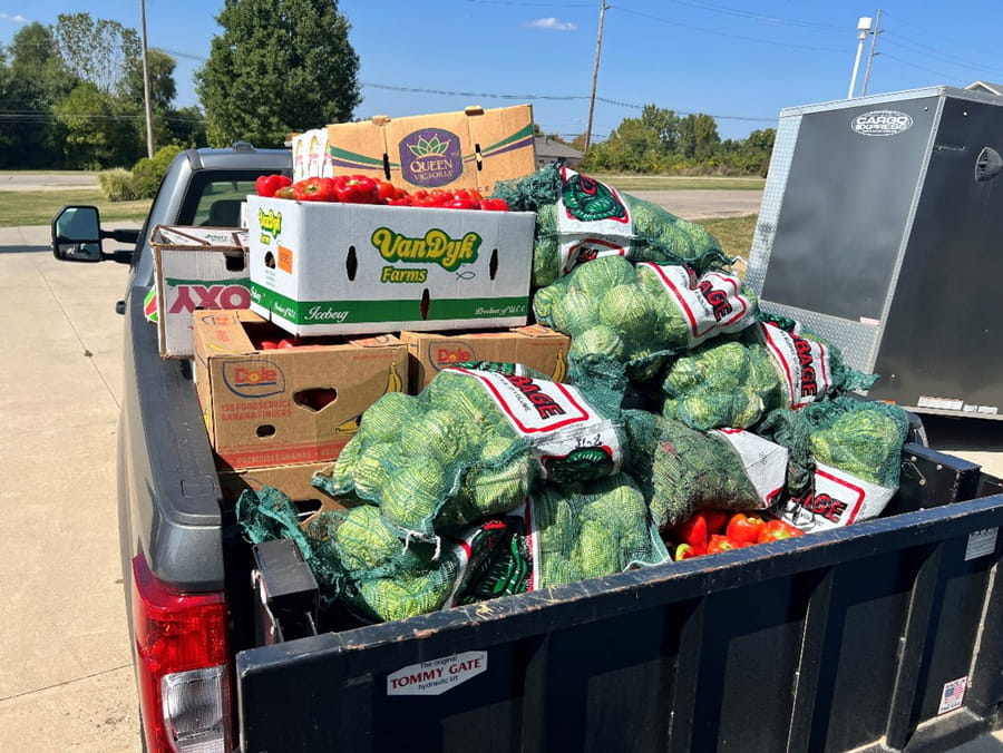 Bags of fresh cabbages and boxes of freshly grown tomatoes in the cab of a truck.