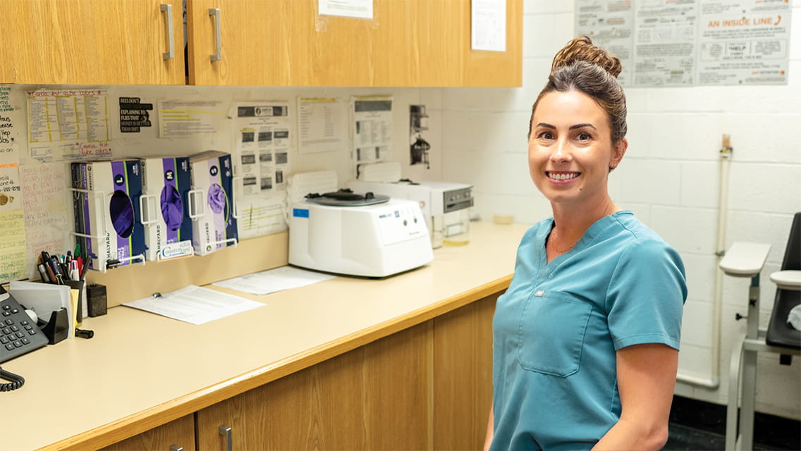A female nurse in her scrubs standing inside a medical lab.