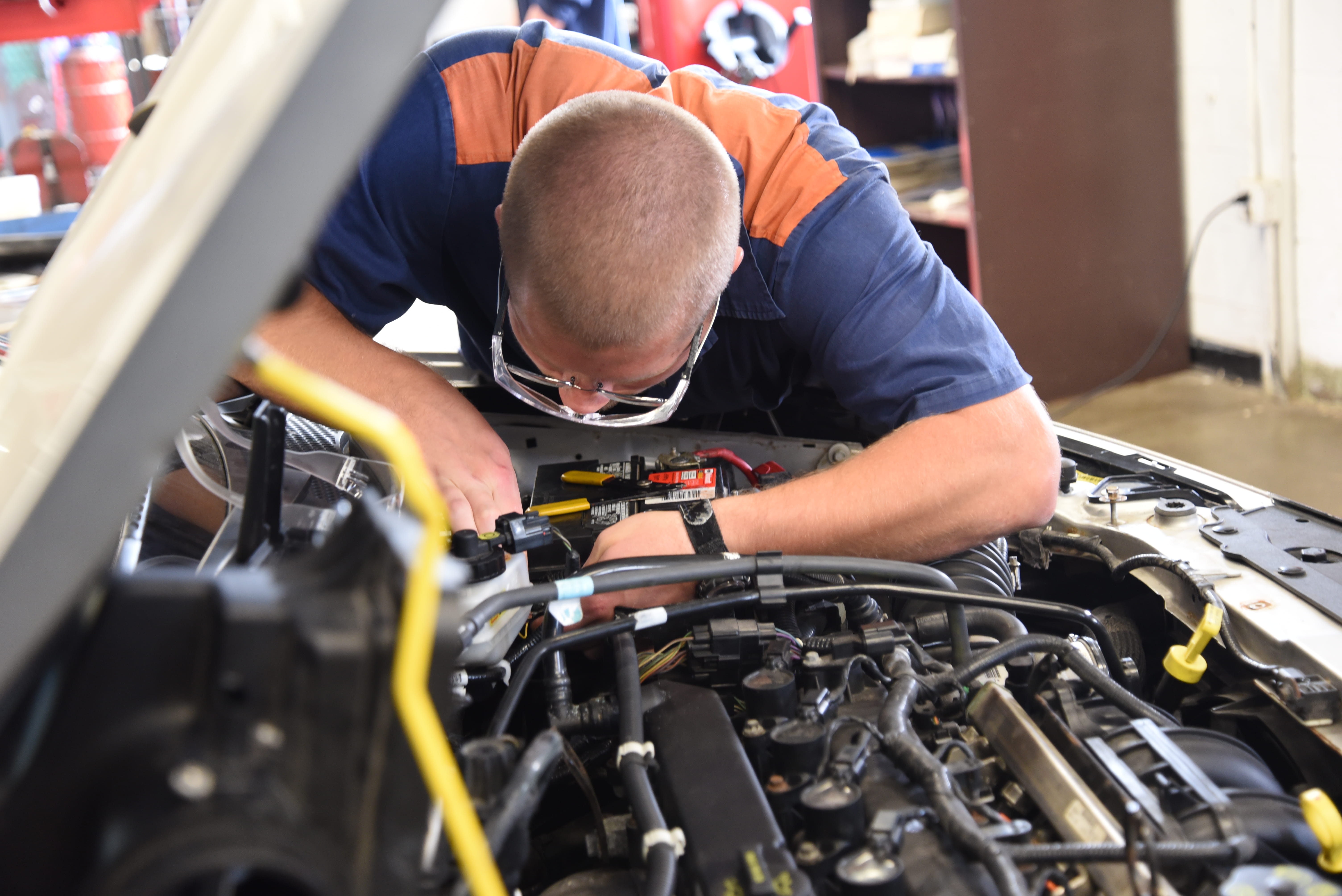 Photo of a prisoner working on the engine of a car.