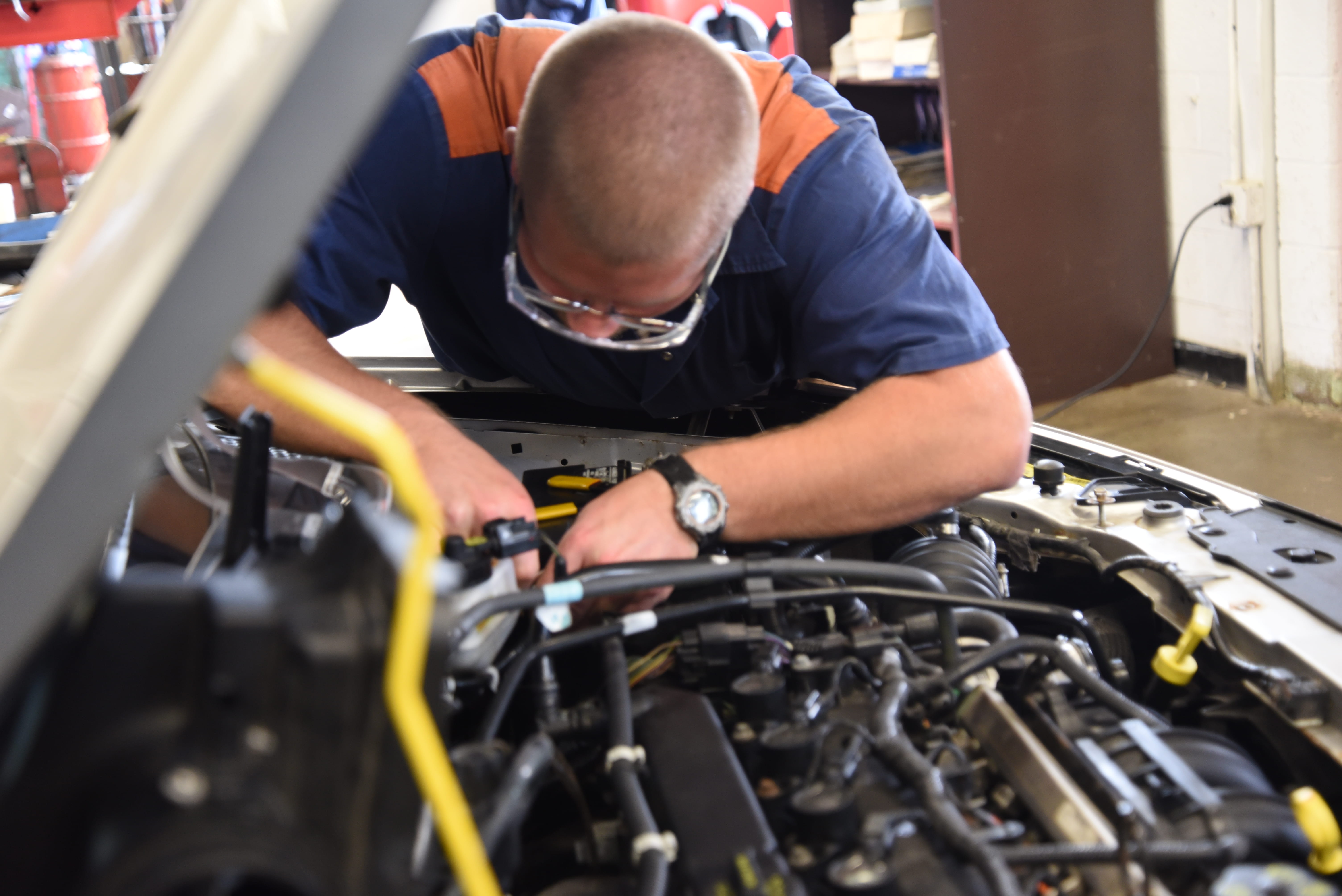 Photo of a prisoner working on the engine of a car.