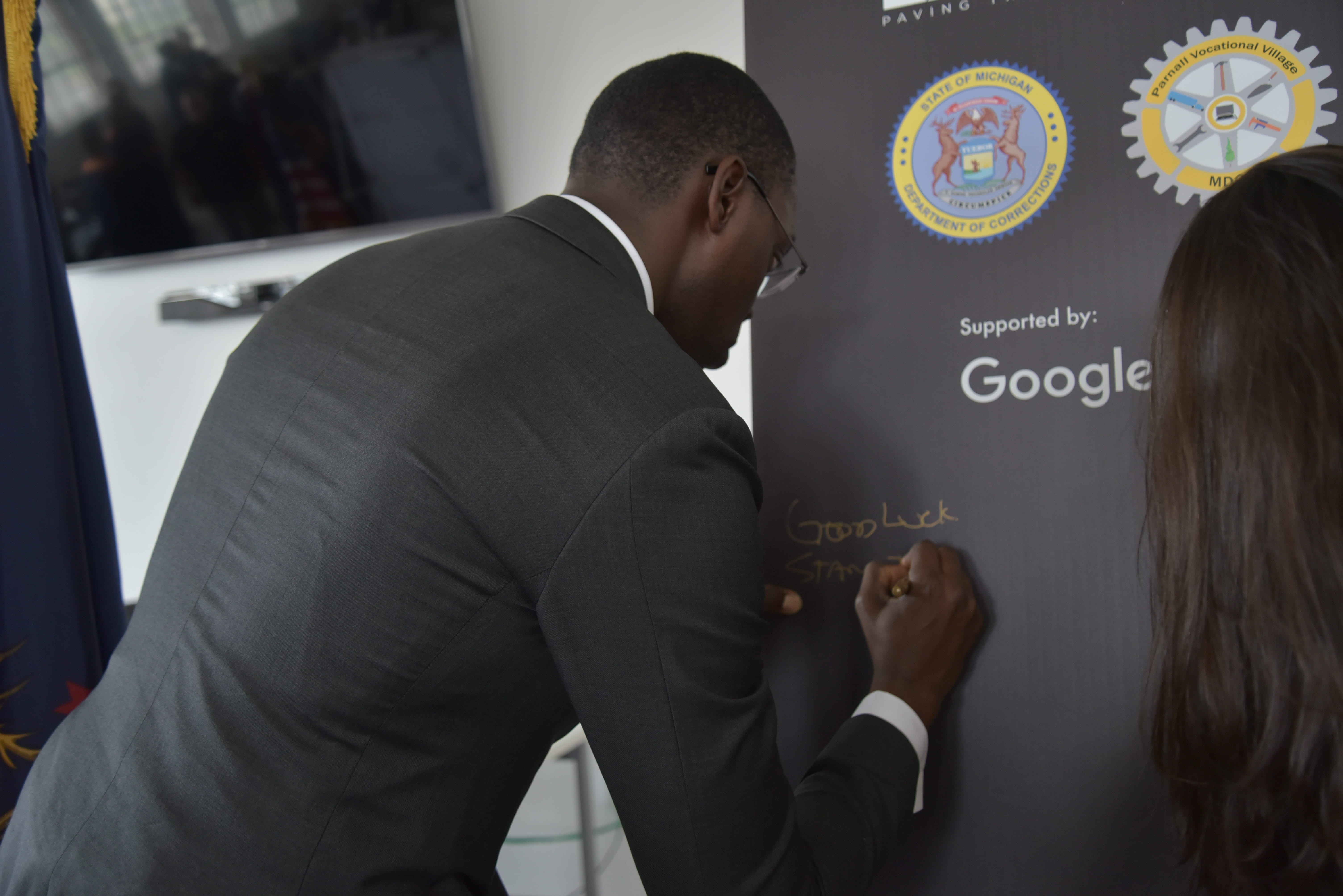 Photo of Lt. Governor Gilchrist signing a poster.
