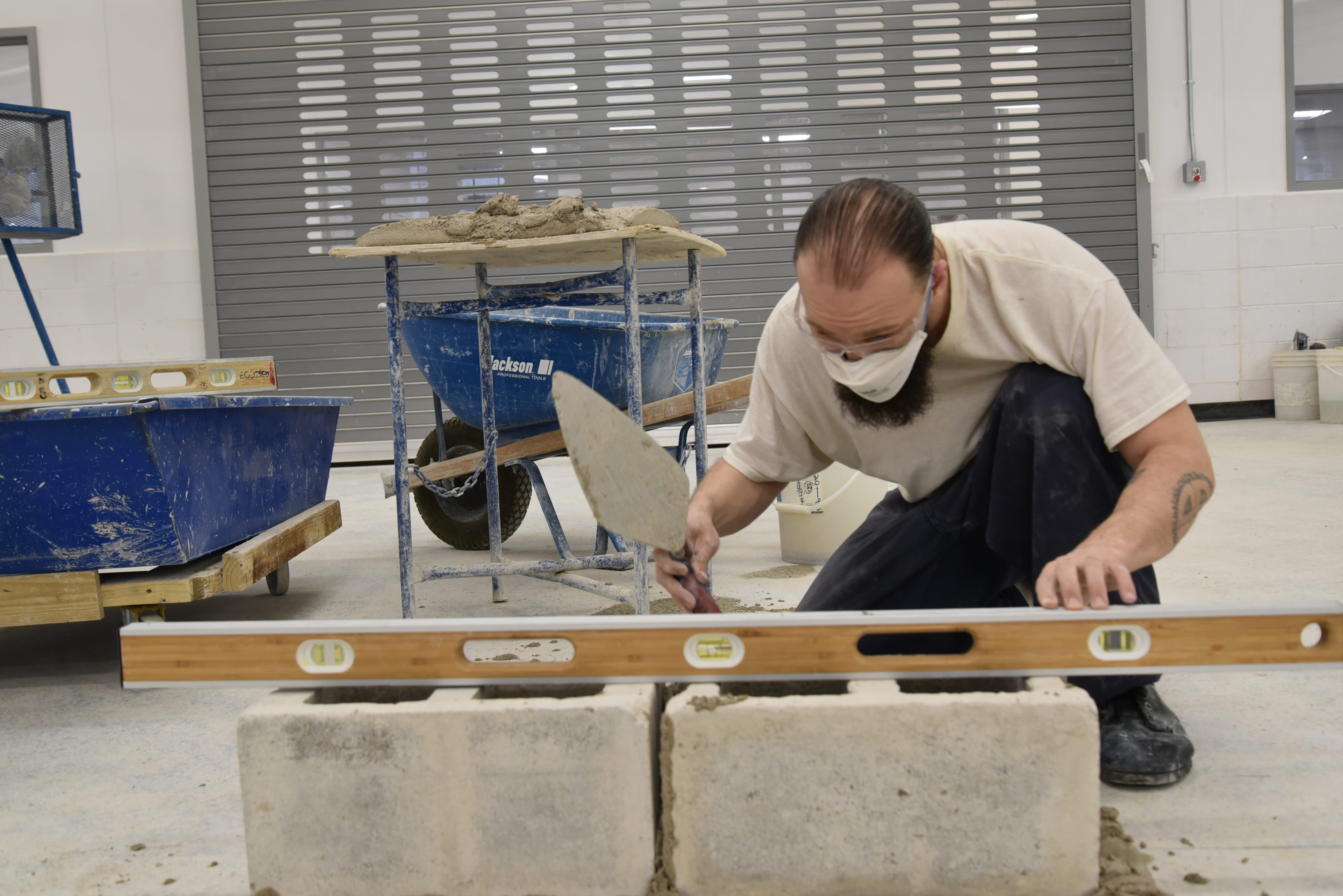 Photo of a prisoner leveling concrete and bricks.