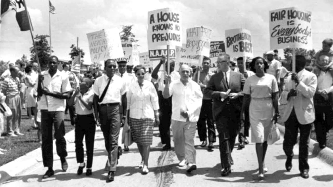 Demonstrators holding signs and walking promoting the Civil Rights movement in Detroit in black and white.
