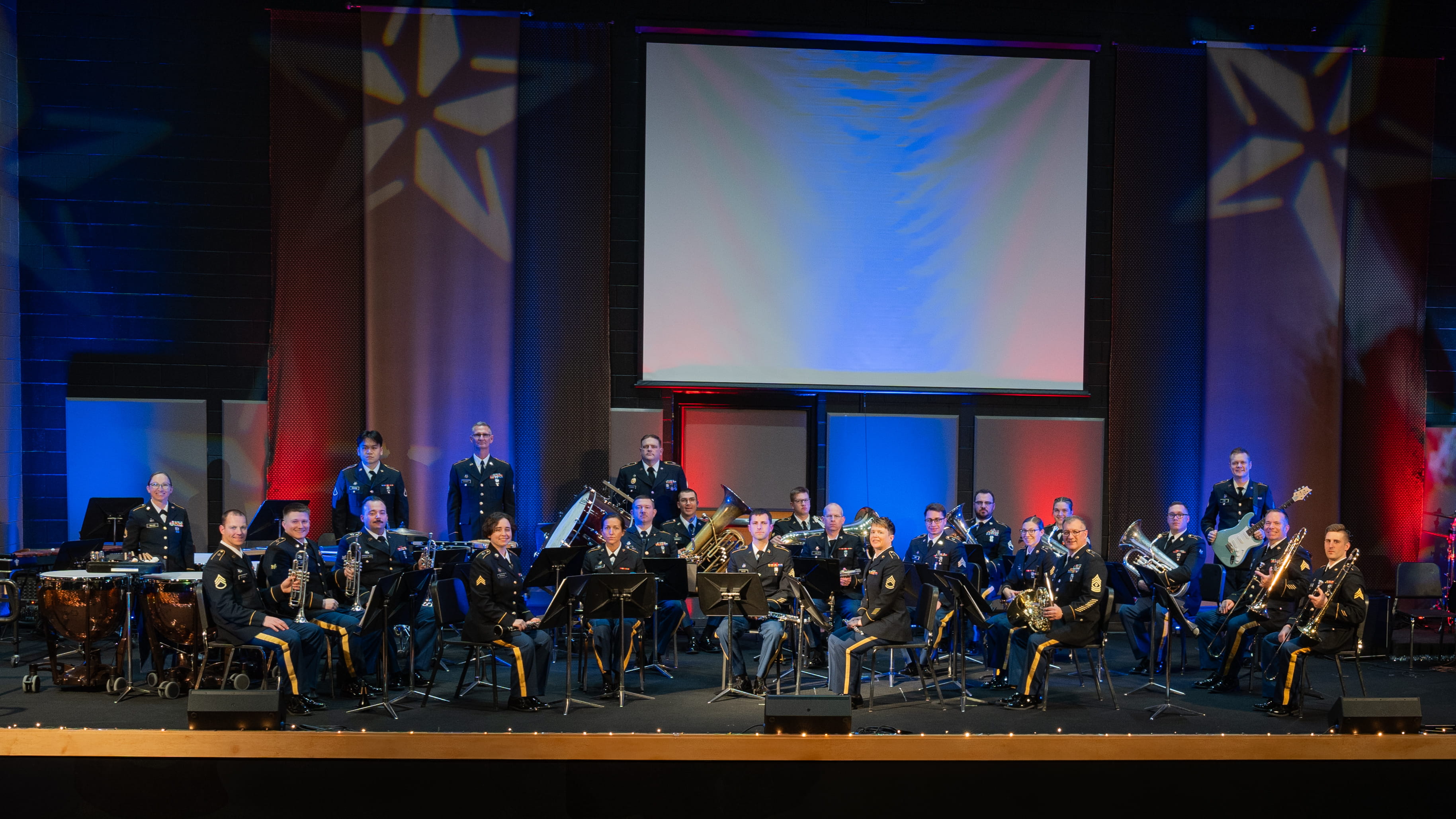 service members in uniform on stage with presentation screen above