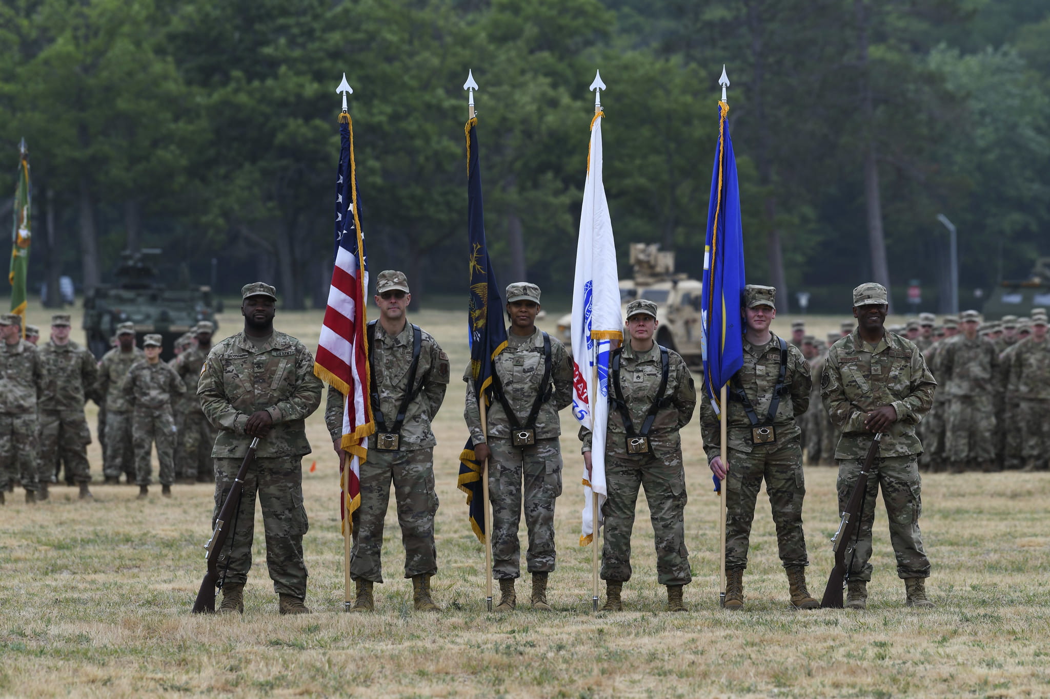 army soldiers standing in a field holding flags for a ceremony