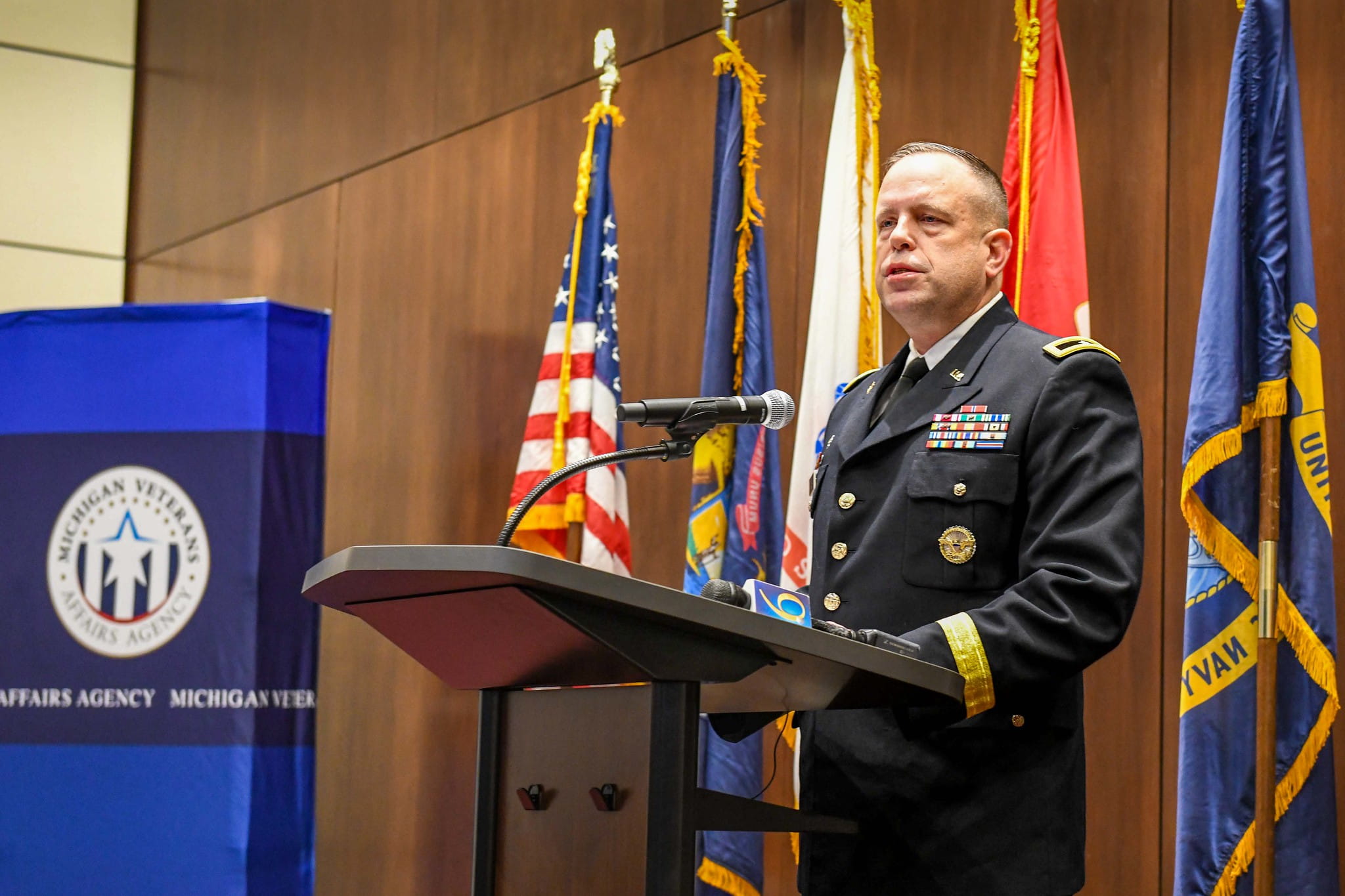 general house in military uniform standing at a podium delivering a speech