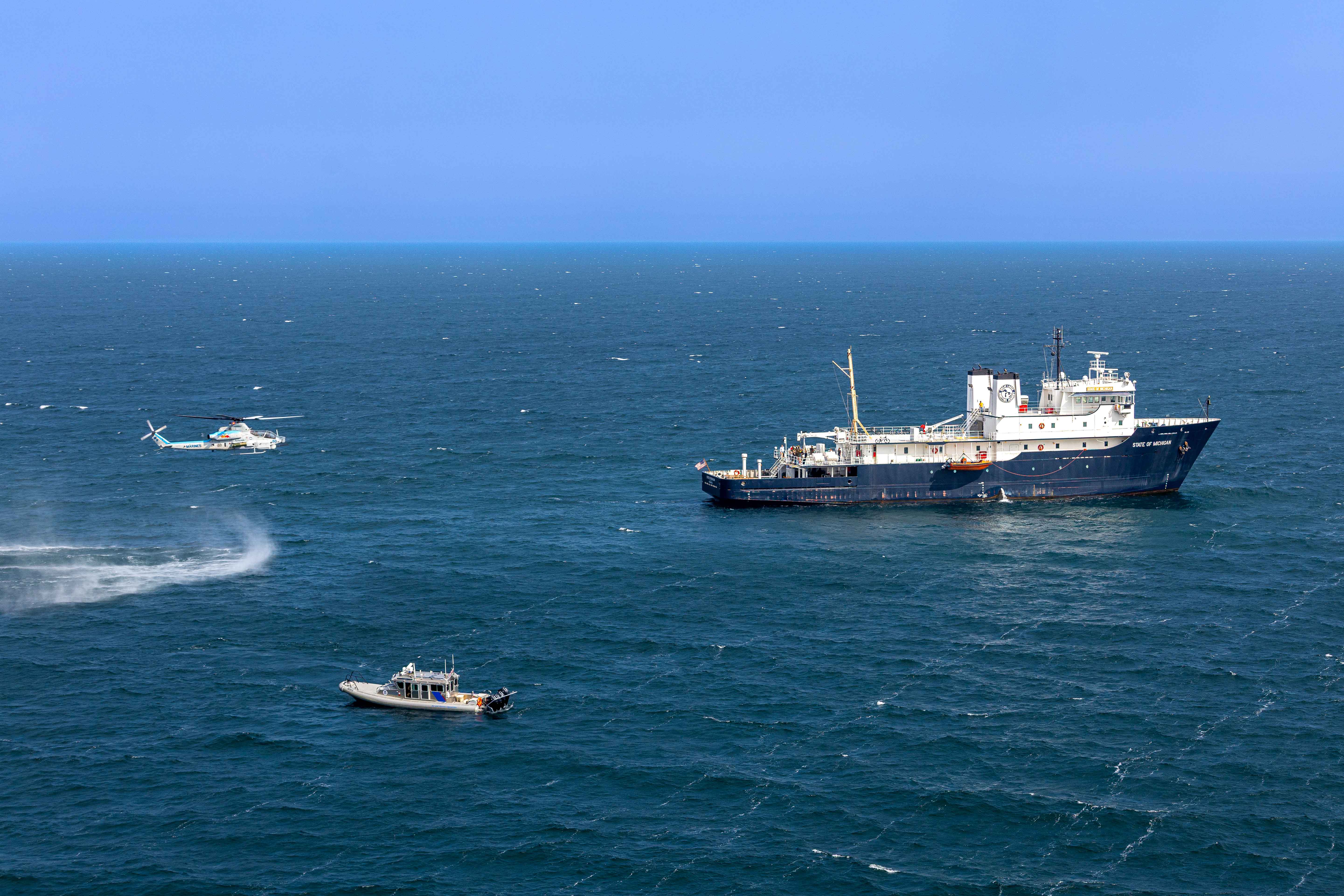 tanker, helicopter and small boat in middle of lake