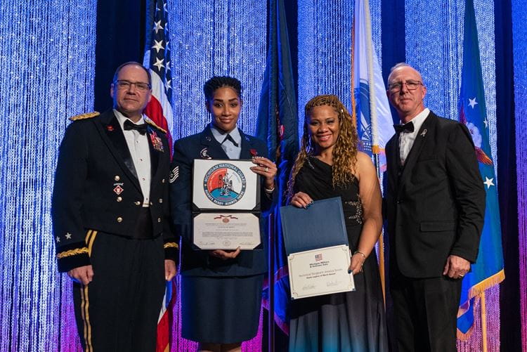 Award recipients stand on stage at the gala displaying their certificate