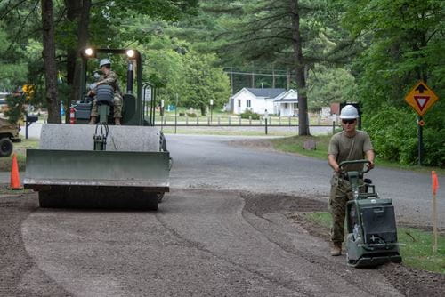 Michigan National Guard soldiers operate heavy machinery while repairing a road