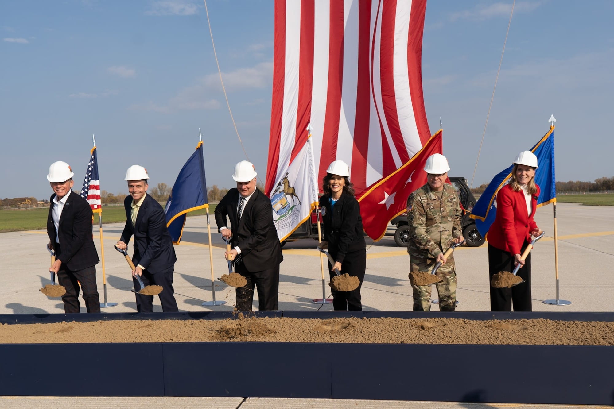 Representatives from Michigan shovel dirt at a runway.