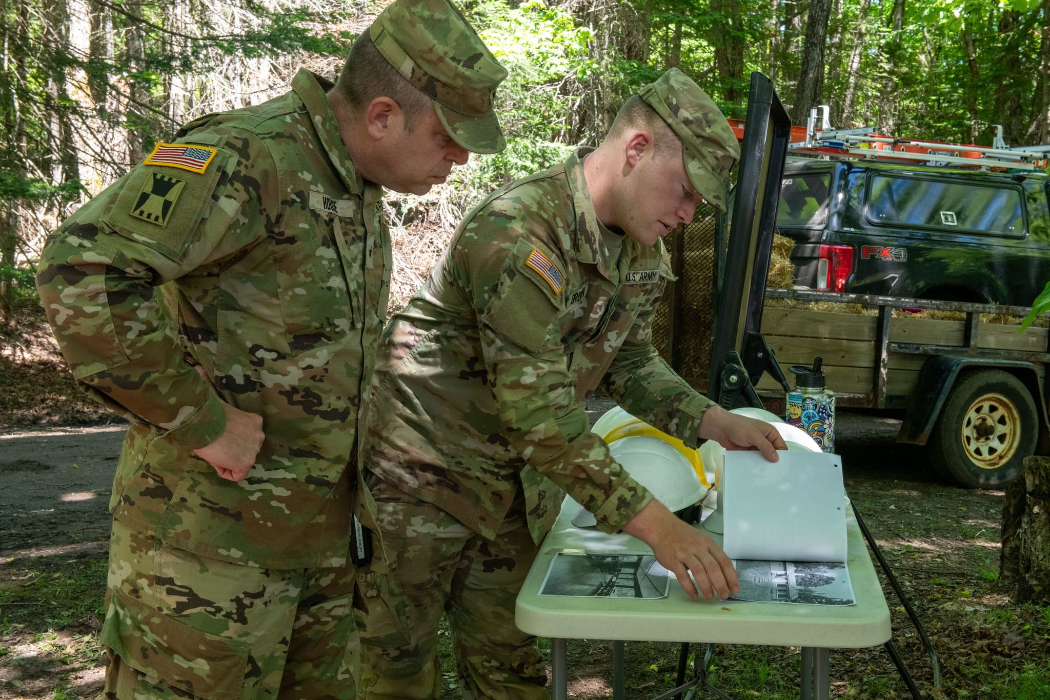 two soldiers look at plans on a table