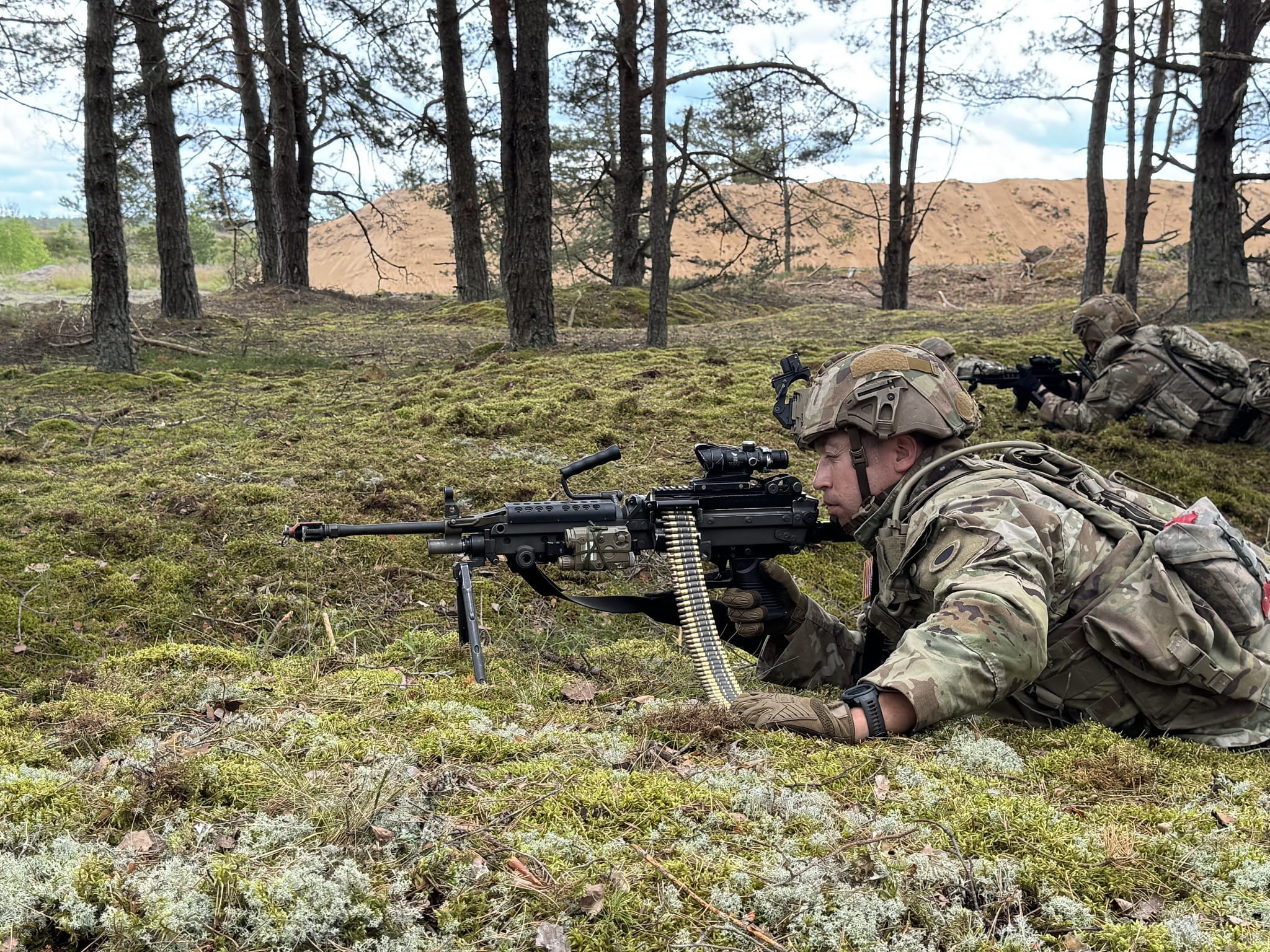 soldier lies on the ground with rifle in hand