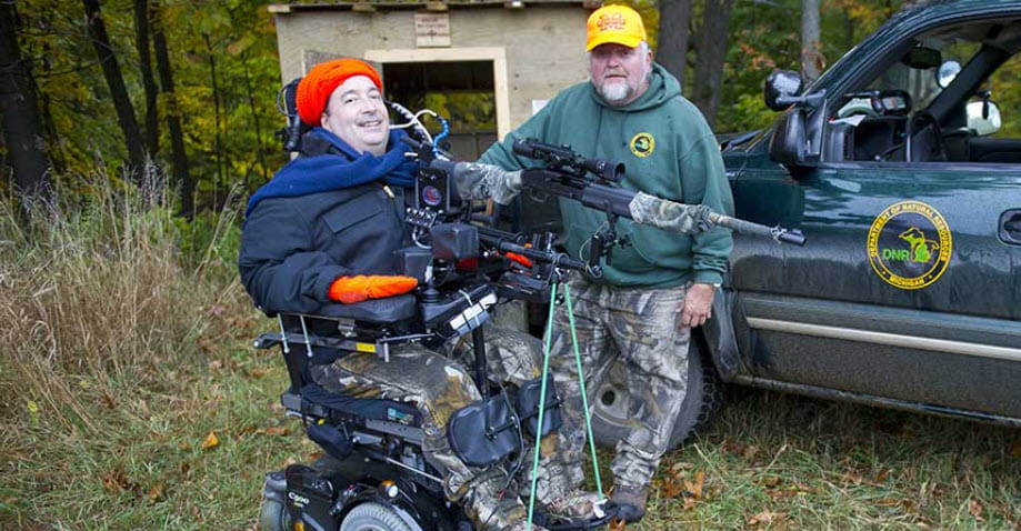 A hunter with a DNR staff member after a successful hunting tip, standing in front of DNR truck
