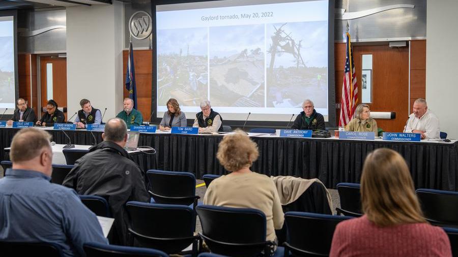 The Natural Resources Commission members sit at a table in the front of an auditorium with members of the public sitting in seats watching their presentation