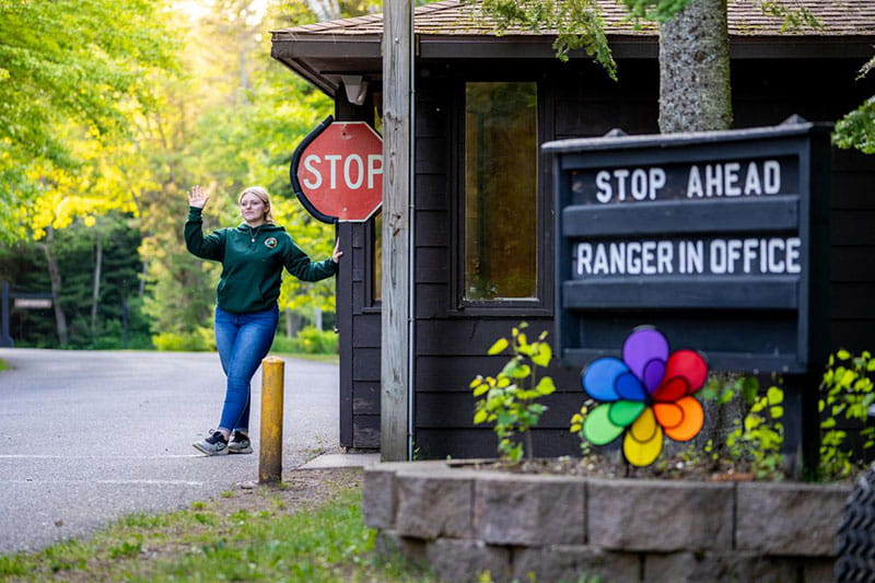 A DNR worker waves at a park entrance as she checks in campers and day users