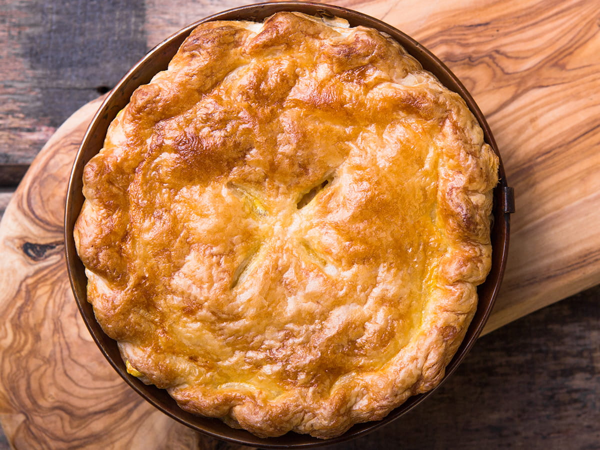 Cooked pot pie on wooden cutting board