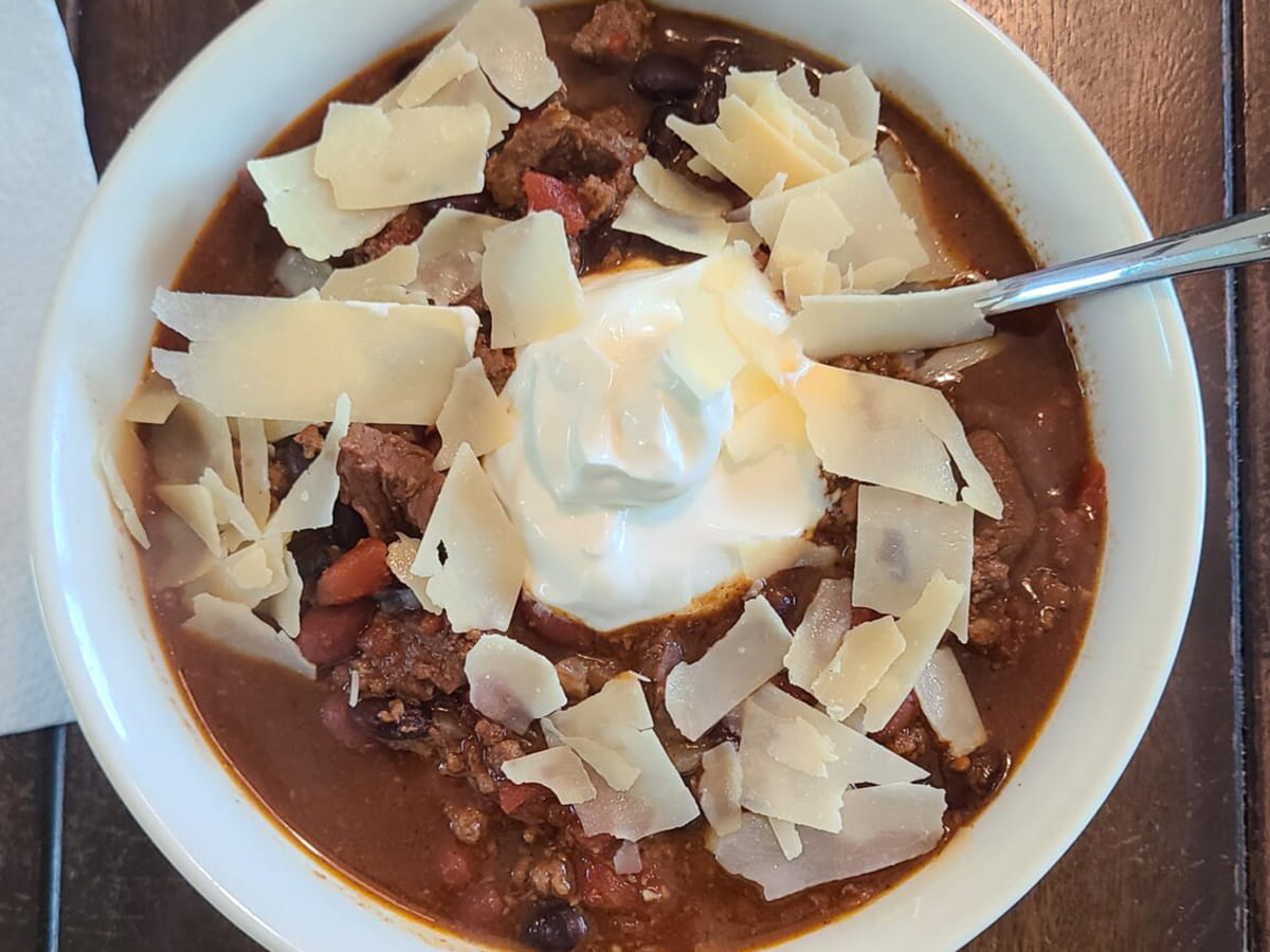 bowl of chili topped with shredded cheese and sour cream