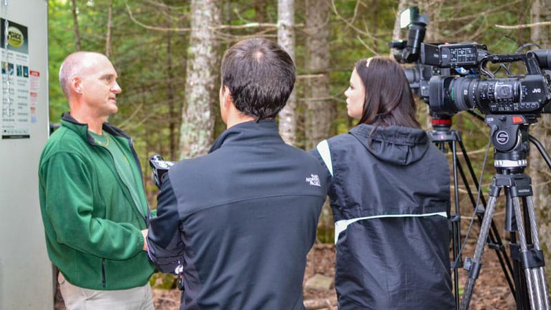 A DNR staff member being interviewed by two news people with a video camera set up