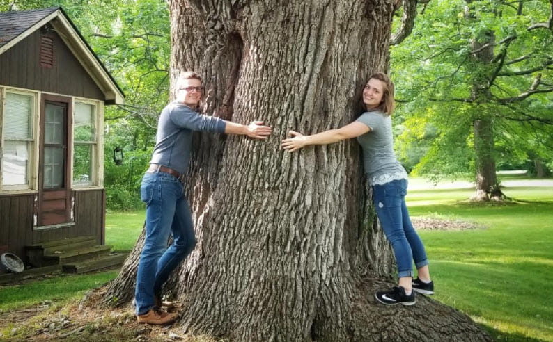Two people wrapping their arms around a big tree