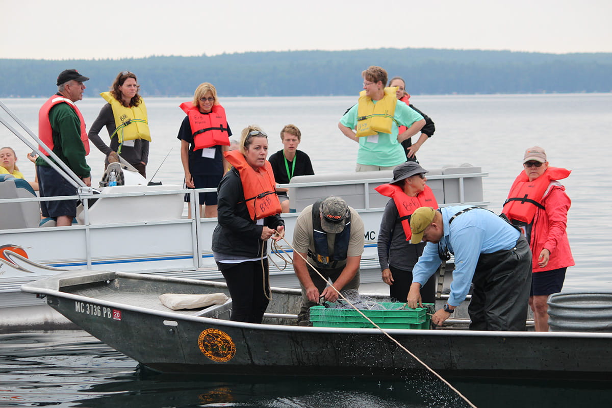 teachers working with DNR biologists to pull in nets from a boat