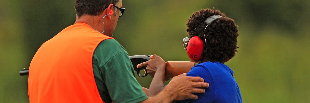 An instructor shows a youth how to shoot
