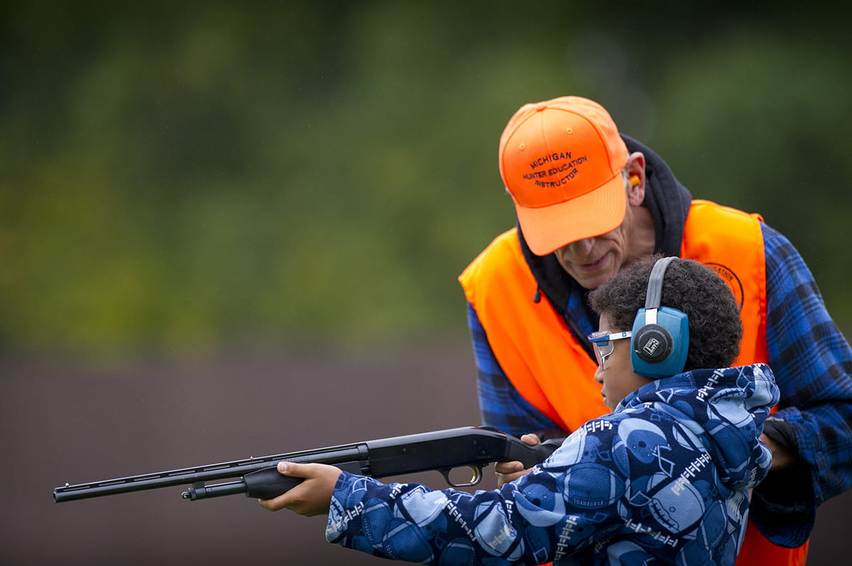 instructor teaching boy with firearm