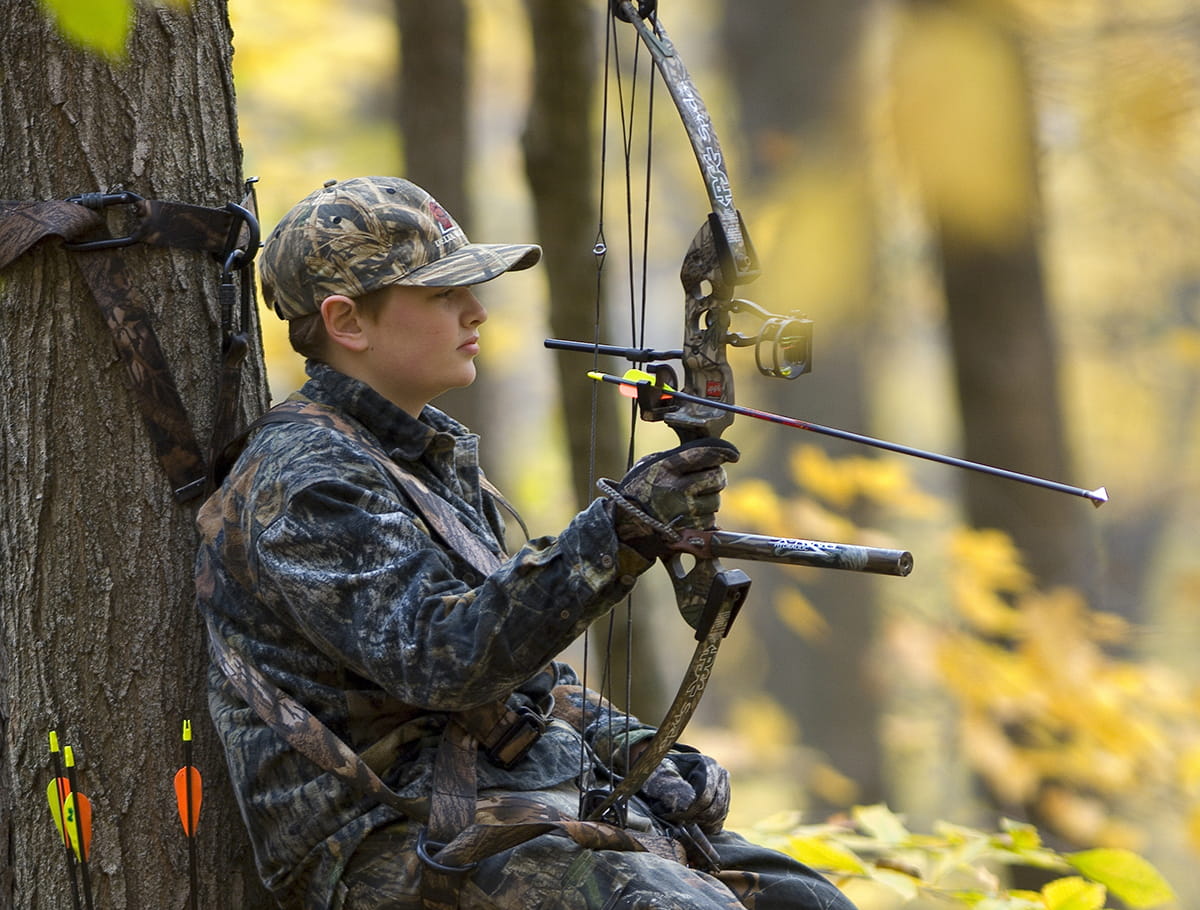 Boy bow hunting in woods
