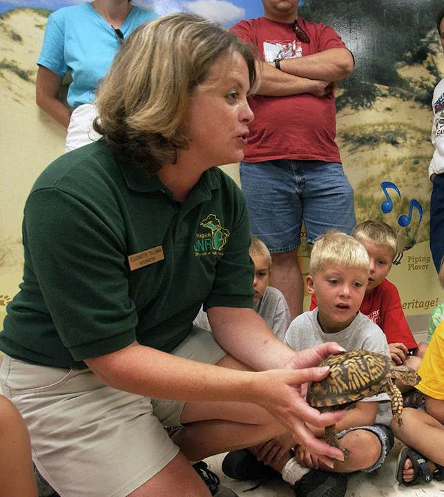 A nature educator shares a turtle with young audience