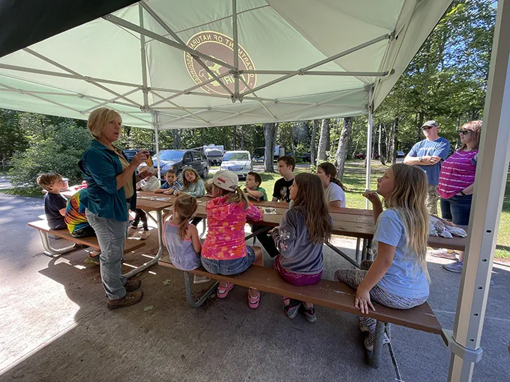 A group of children at a picnic table being led by an instructor