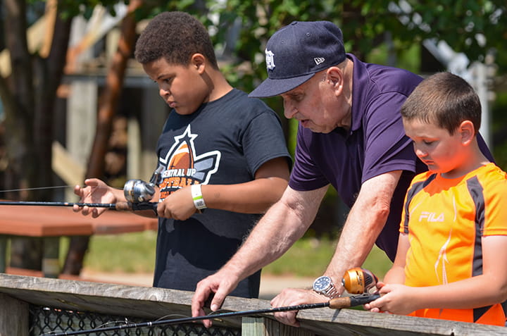 Two young boys with an older man fish at the Pocket Park