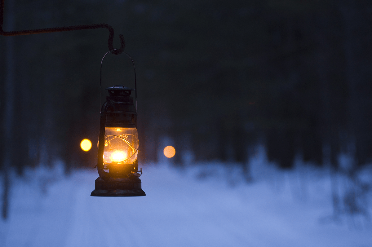 A lantern on a snowy trail at night in the winter