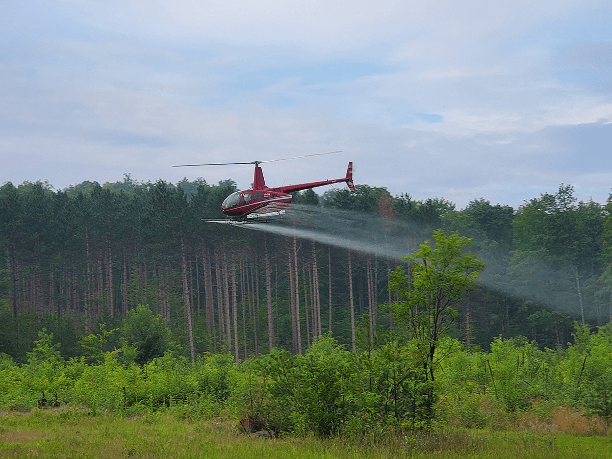 helicopter spraying herbicide over field
