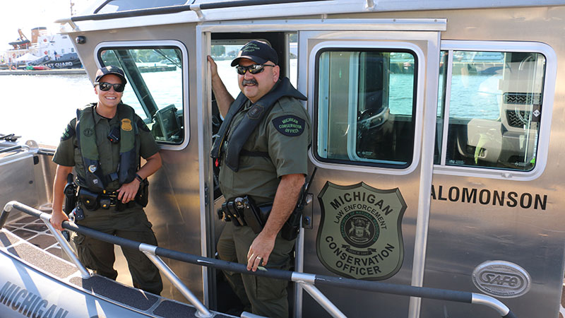 Two conservation officers on patrol on a boat in the water