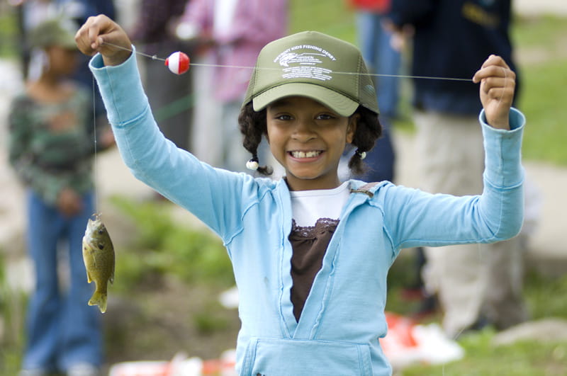 a child holds up a fish that she caught