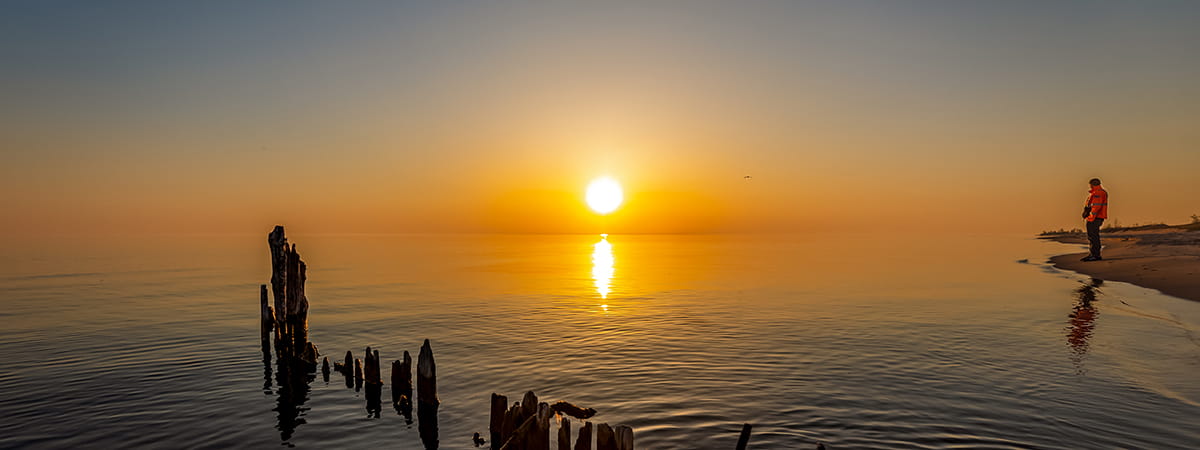 Man looking over water at sunset