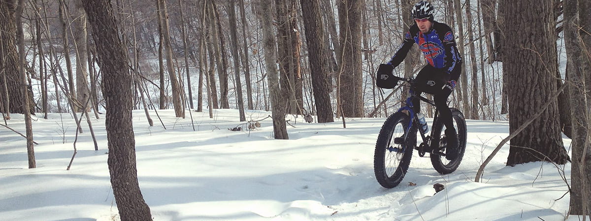 man riding fat-tire bike on snowy trail