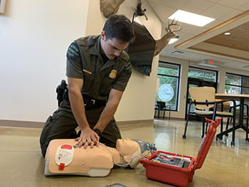 man practices cpr on a baby mannequin in a building lobby
