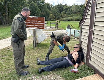 instructor watches a student practice first aid on a scenario victim