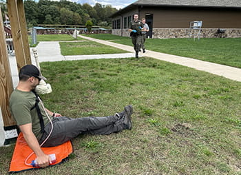 student and instructor run towards a injured scenario actor sitting on ground 