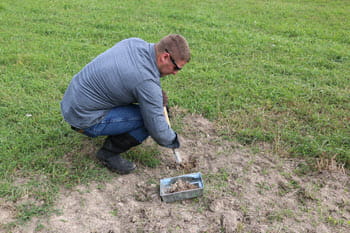 A man digs in the dirt to place a foothold trap