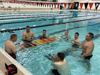 group of men stand in a pool around a backboard