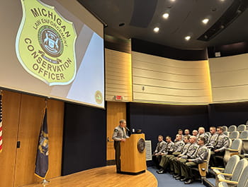 Person stands at the podium on a stage speaking to people in a auditorium