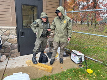 Two men outside in the rain looking at a phone