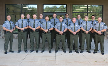 group of officers smiling, standing outside in front of a building