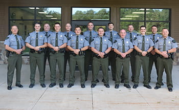 group of officers smiling, standing outside in front of a building