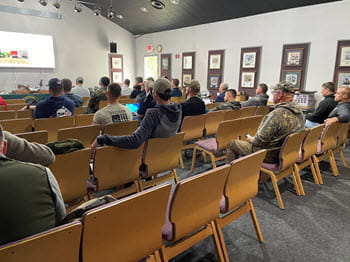 people sitting on chairs in a room watching a presentation