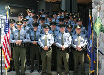 group of people stand on stairs, smiling outside of a building