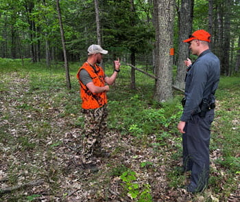 student talks to a instructor in the woods during a scenario