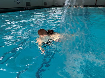 Person pulling another person through the pool